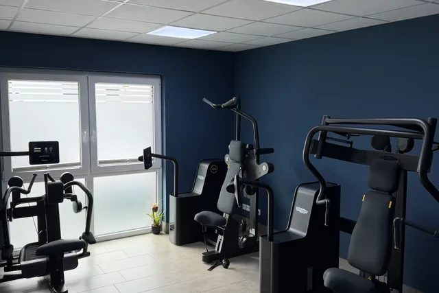 Trainingsraum mit Technogym-Geräten vor dunkelblauer Wand