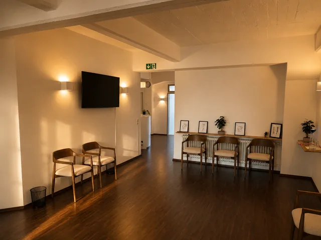 Wartebereich mit Stühlen entlang der Wand unter den offenen Deckenbalken