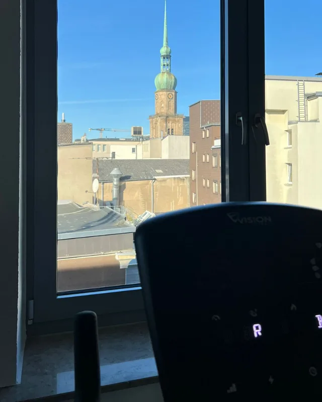 Blick aus dem Trainingsraum über die Dächer auf den Turm von St. Reinoldi, davor die Konsole eines Laufbands