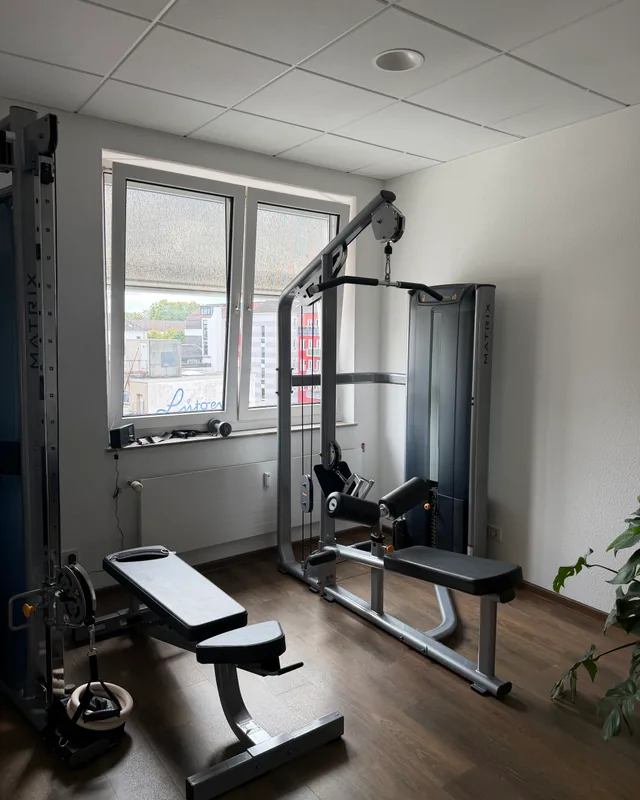 Trainingsgerät und Bank am Fenster mit Blick auf die Nachbarhäuser