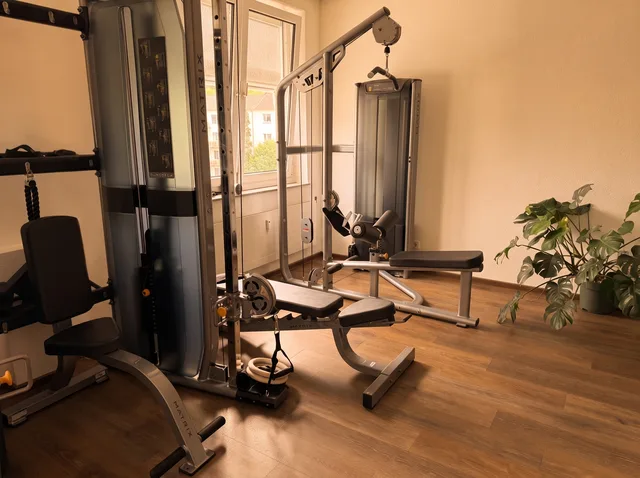 Trainingsfläche mit zwei Kabelzuggeräten und Trainingsbank am Fenster