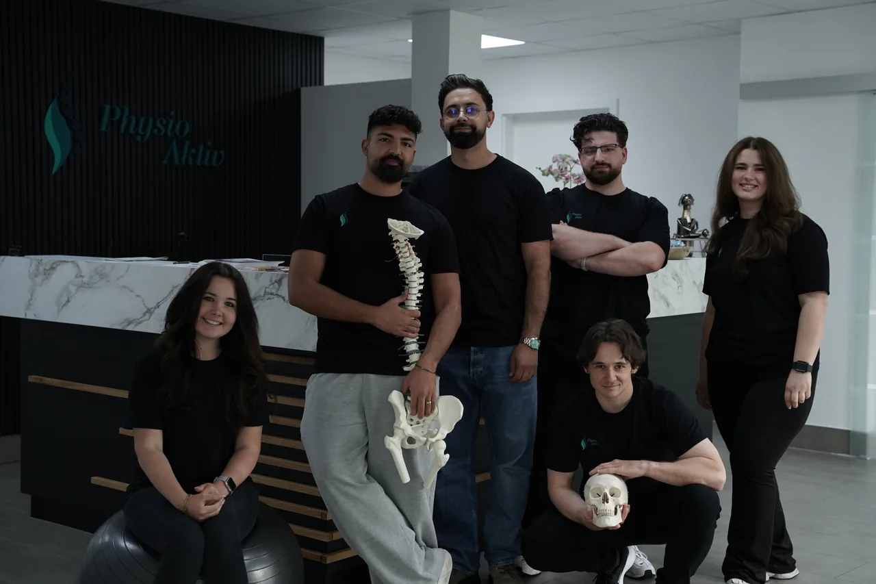 Das Team von PhysioAktiv vor dem Empfang, sechs Personen in schwarzen Praxisshirts