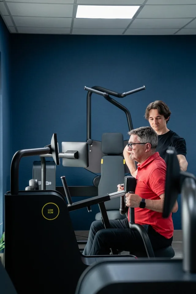 Übung an einem Trainingsgerät, von einem Therapeuten begleitet